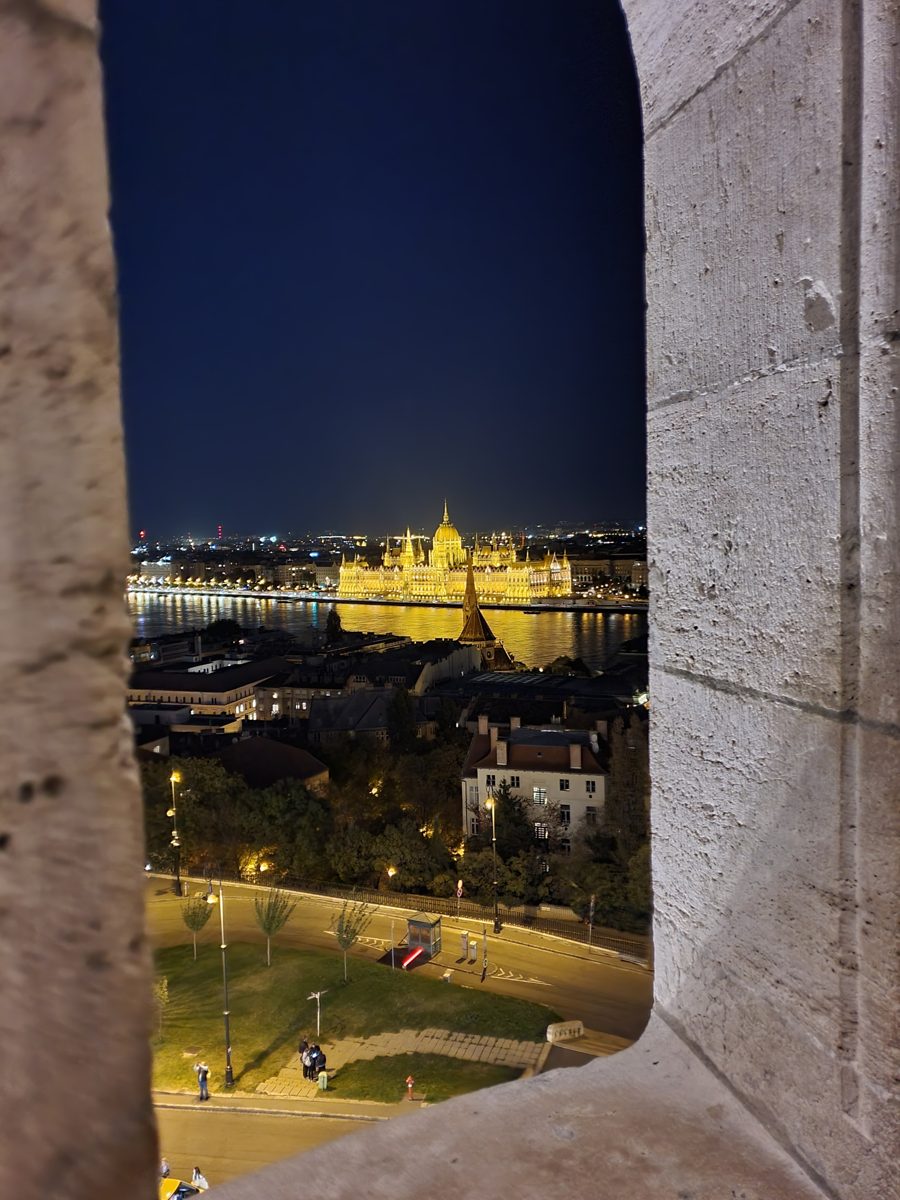 The lit-up Hungarian Parliament framed by an arch of Fisherman's Bastion at night