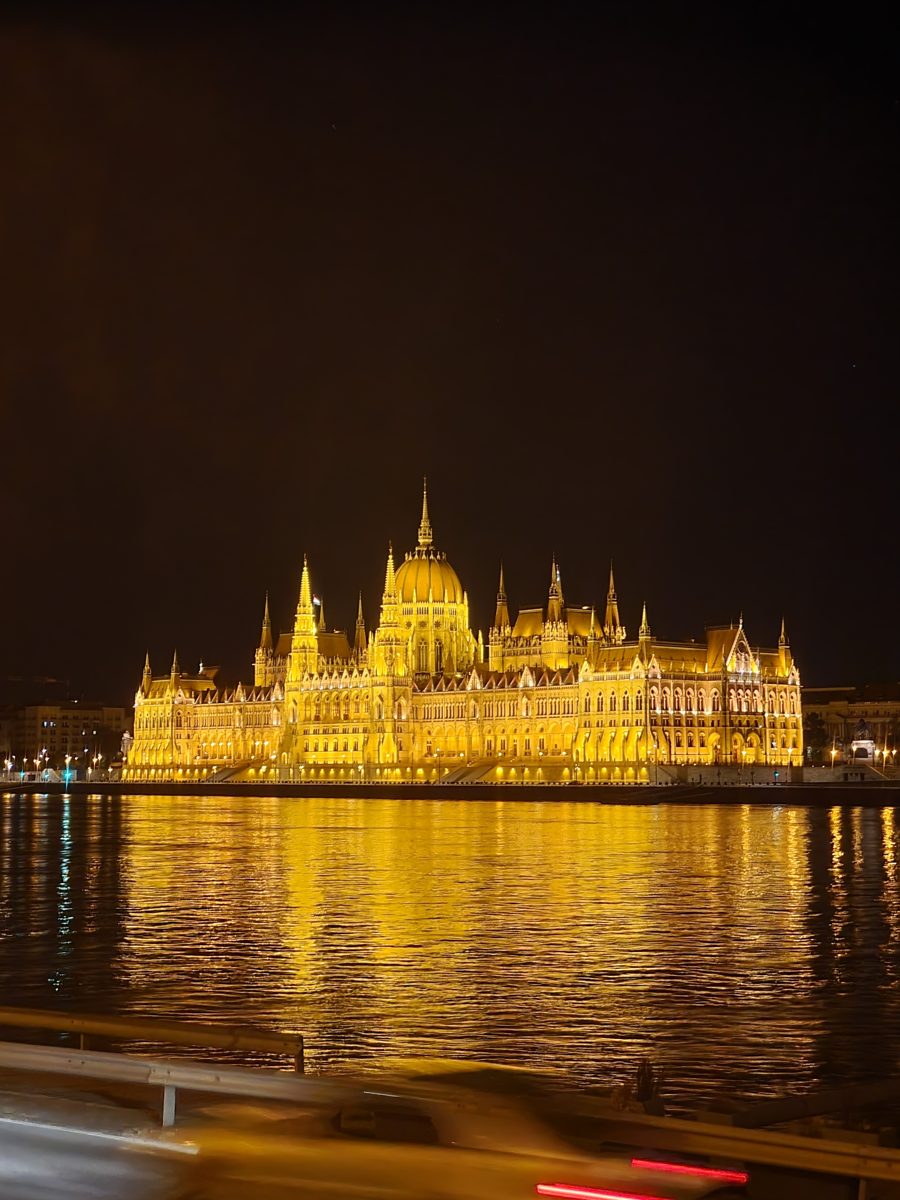 Hungarian Parliament building lit up gold over the Danube at night, seen from the Buda side