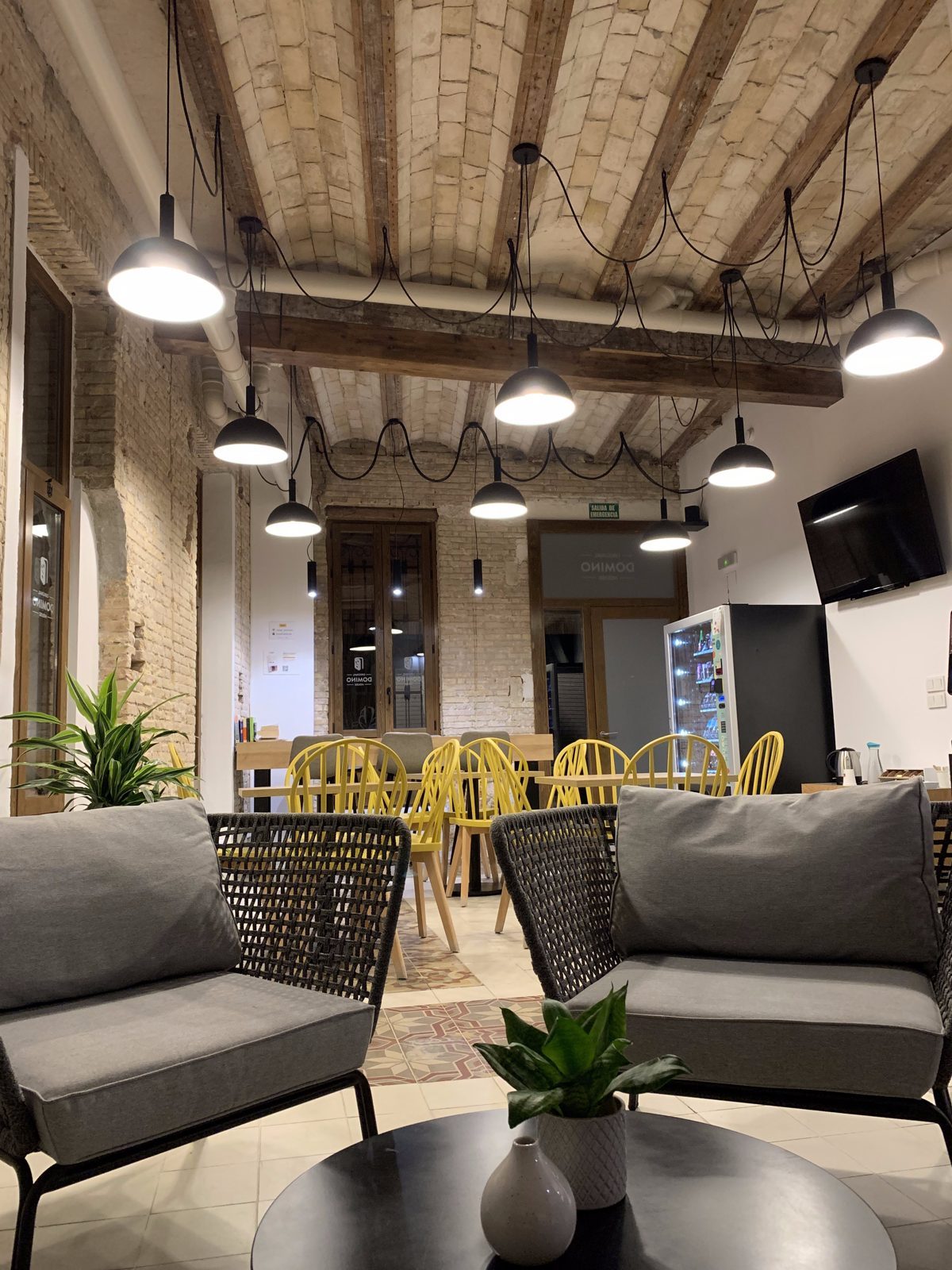 Lobby of Original Domino House hotel in Valencia, with brick walls and wooden beams