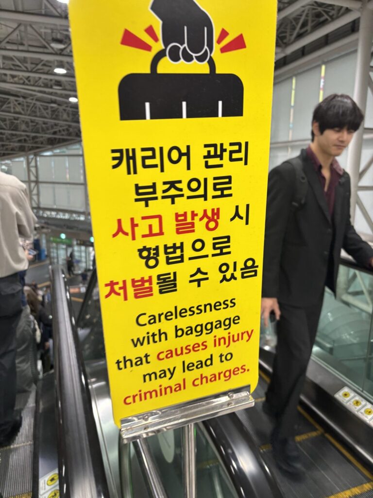 Sign at Seoul Station escalator warning that carelessness with baggage can lead to criminal charges