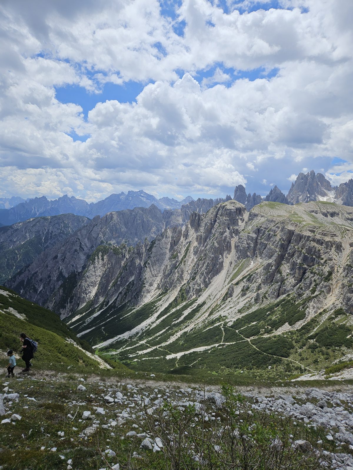 Hikers on the Tre Cime trail above a wide rocky valley